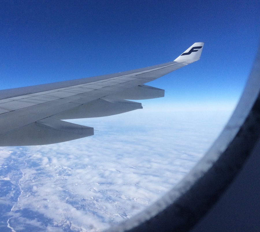 Lentokoneensiipi pilvien päällä sinisellä taivaalla.