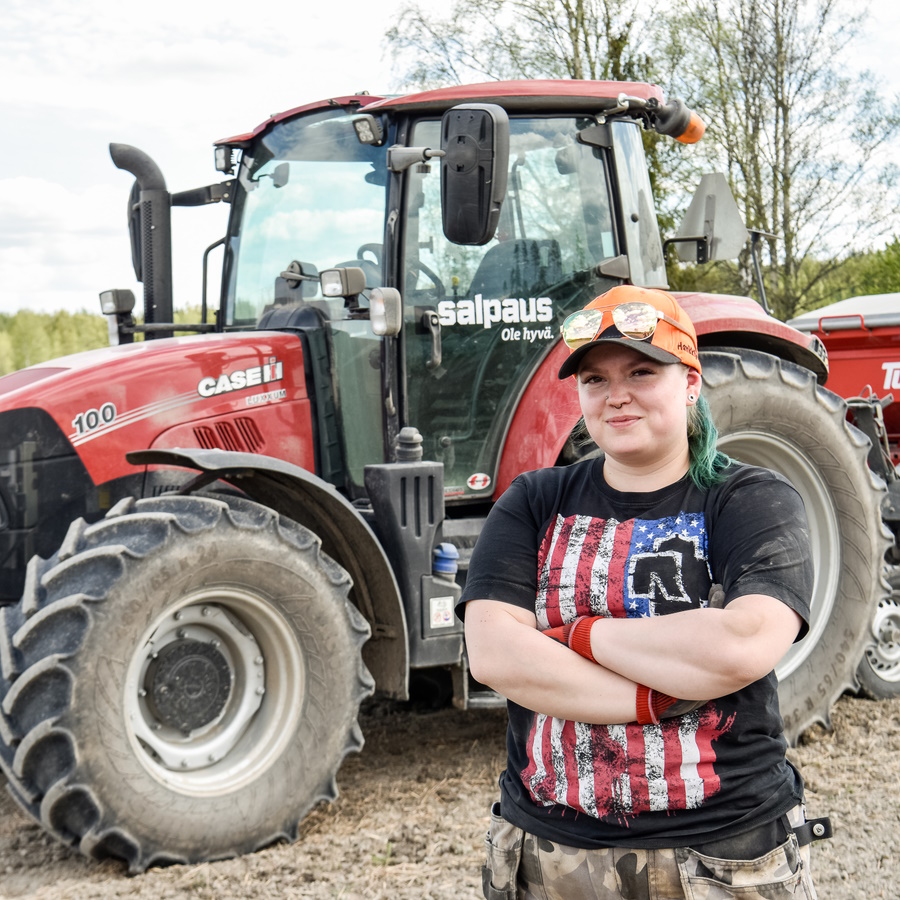 Nuori henkilö seisoo traktorin edessä.