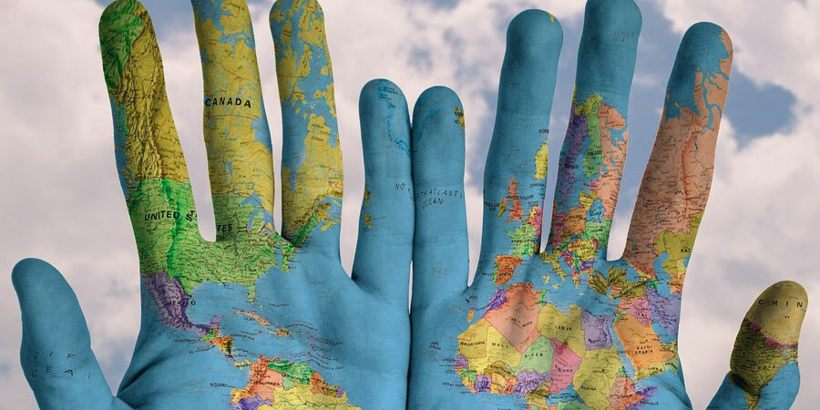 Kaksi kättä, johon on maalattu maailman kartta.