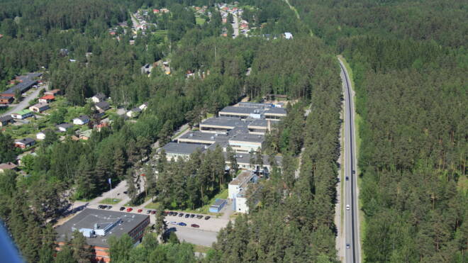 Ilmakuva Heinolan kampuksesta jossa on metsän läpi kulkeva tie. Rakennukset ovat puiden keskellä sekä parkkipaikka.