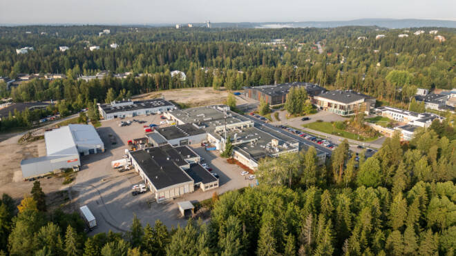 Ilmakuva Vipusenkadun kampuksesta, jota ympäröi tiheä vihreä metsä. Alueella on useita suuria suorakaiteen muotoisia rakennuksia, pysäköintialueita ja ajoneuvoja.